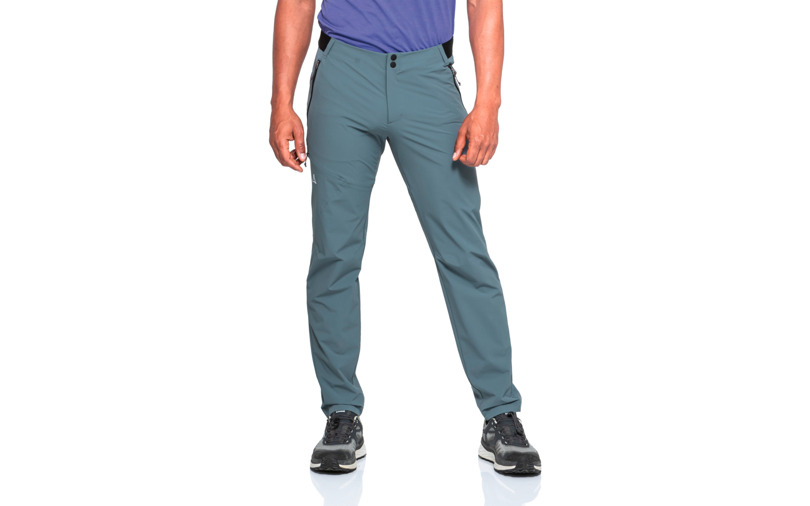 Unterkörper einer stehenden Person von Hüfte bis Fuß, trägt blaugrüne Hose, oberer Saum eines violetten T-Shirts sichtbar, schwarze Sportschuhe mit weißer Sohle, Hände seitlich sichtbar