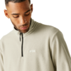 Person looking down, wearing a light beige quarter-zip fleece with a small white chest logo