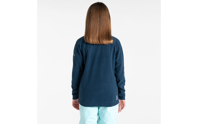 Kind mit langen braunen Haaren, steht mit dem Rücken zur Kamera, trägt blaues Oberteil und helle Hose