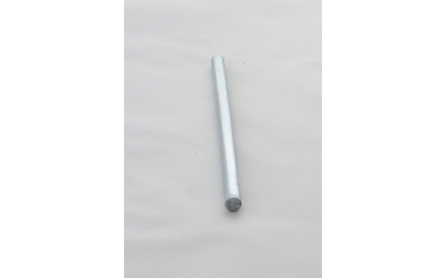 Schlanke silberne Metallstange, diagonal liegend auf hellem, leicht faltigem Hintergrund