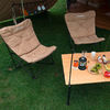 Zwei beige Campingstühle auf grünem Rasen neben einem Holztisch mit Getränkedosen und Spielzeug