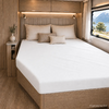 Tweepersoonsbed met kussens in een houten afgewerkte ruimte, nachtkastje met vaas, wandlampen, raam met uitzicht op meer en bergen, gordijn