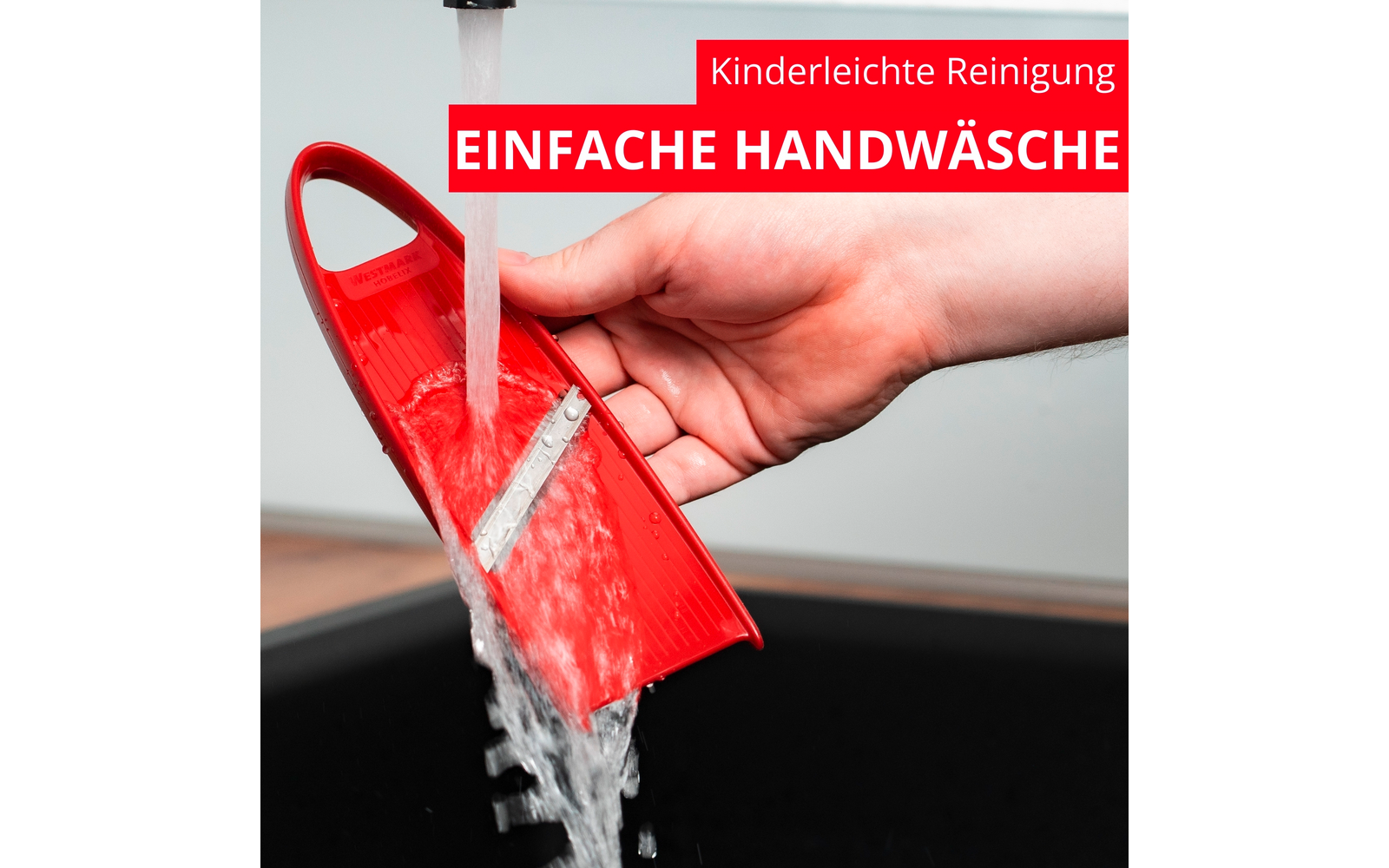 Main tenant une pièce en plastique rouge avec une lame métallique visible sous de l'eau courante au-dessus d'un évier noir ; bannières rouges avec texte blanc Kinderleichte Reinigung et EINFACHE HANDWÄSCHE