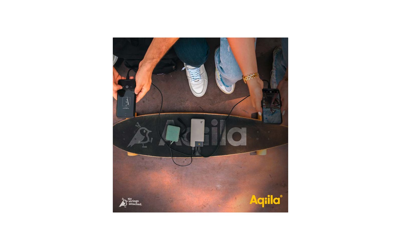 Blick von oben auf ein Skateboard auf dem Boden, umgeben von Beinen und Füßen von drei Personen