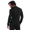 Persona vista da dietro con maglia nera a maniche lunghe e pantaloni neri abbinati, capelli ricci scuri, barba, sfondo bianco