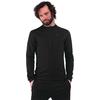 Persona con barba e capelli scuri ricci fino alle spalle, indossa una maglia a maniche lunghe nera e pantaloni neri, mani nelle tasche, sfondo bianco