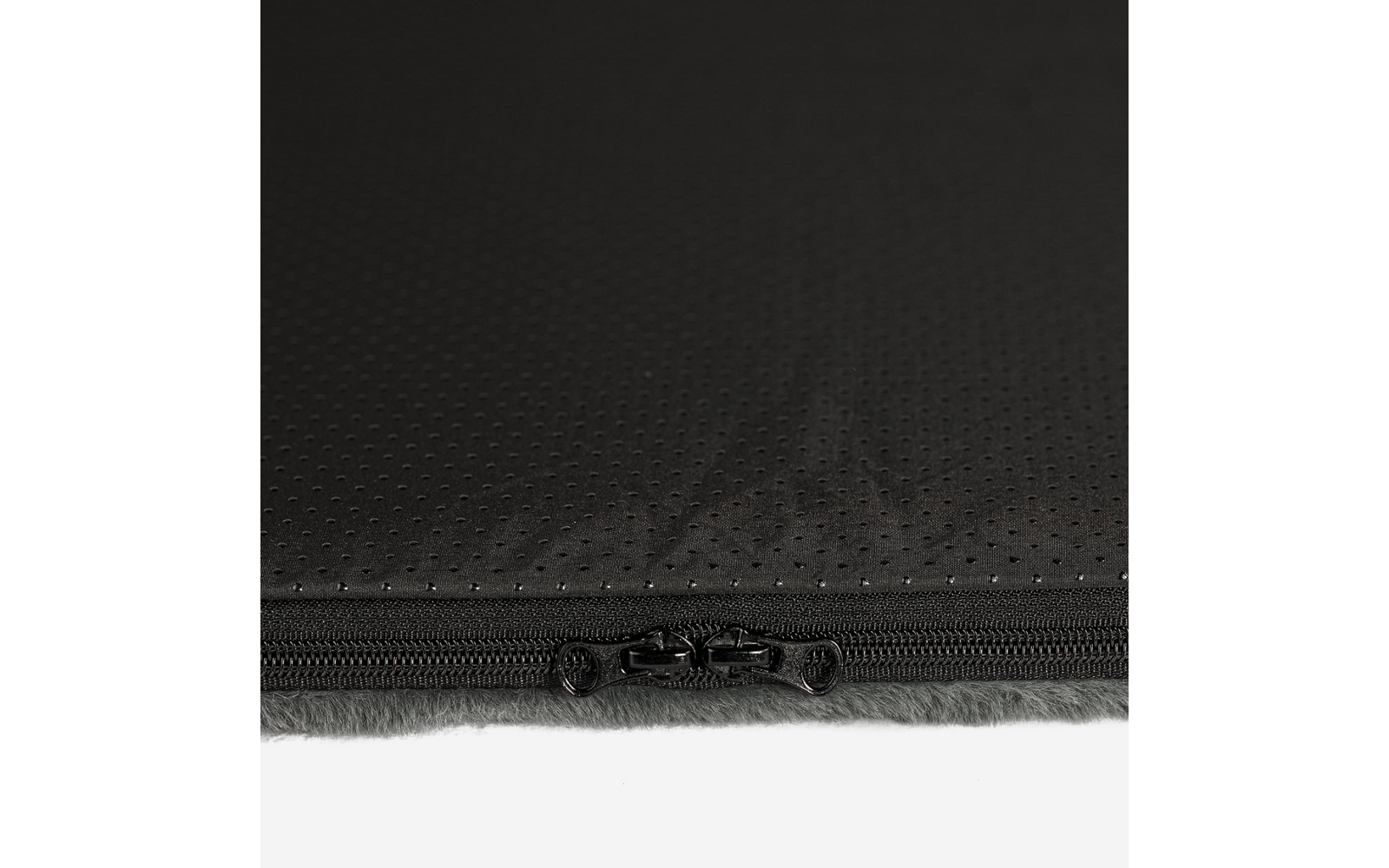 Schwarzer perforierter Stoff, Kante mit zwei schwarzen Reißverschlussschiebern, darunter graues weiches Futter sichtbar