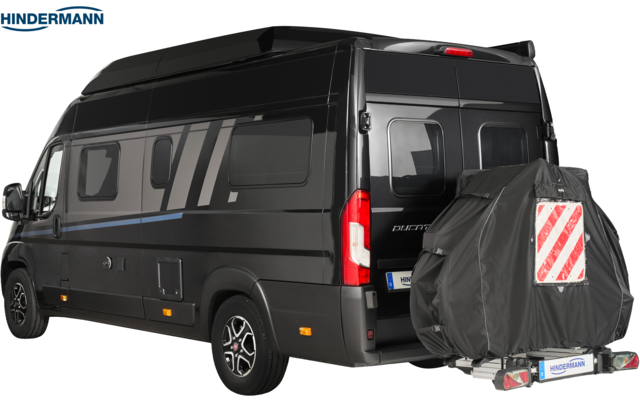 Schwarzer Kastenwagen mit Hochdach und Seitenscheiben, Heckansicht von rechts; montiertes Reserverad mit dunkler Abdeckung und roter-weißer Diagonalwarntafel; Firmenlogo "HINDERMANN" oben links