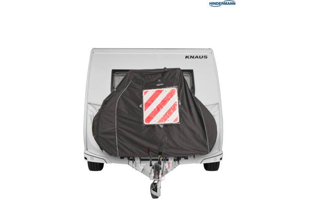 Vorderes Ende eines weißen Wohnwagens mit schwarzer Abdeckung, roter-weißer diagonaler Warntafel und sichtbarer Anhängerkupplung