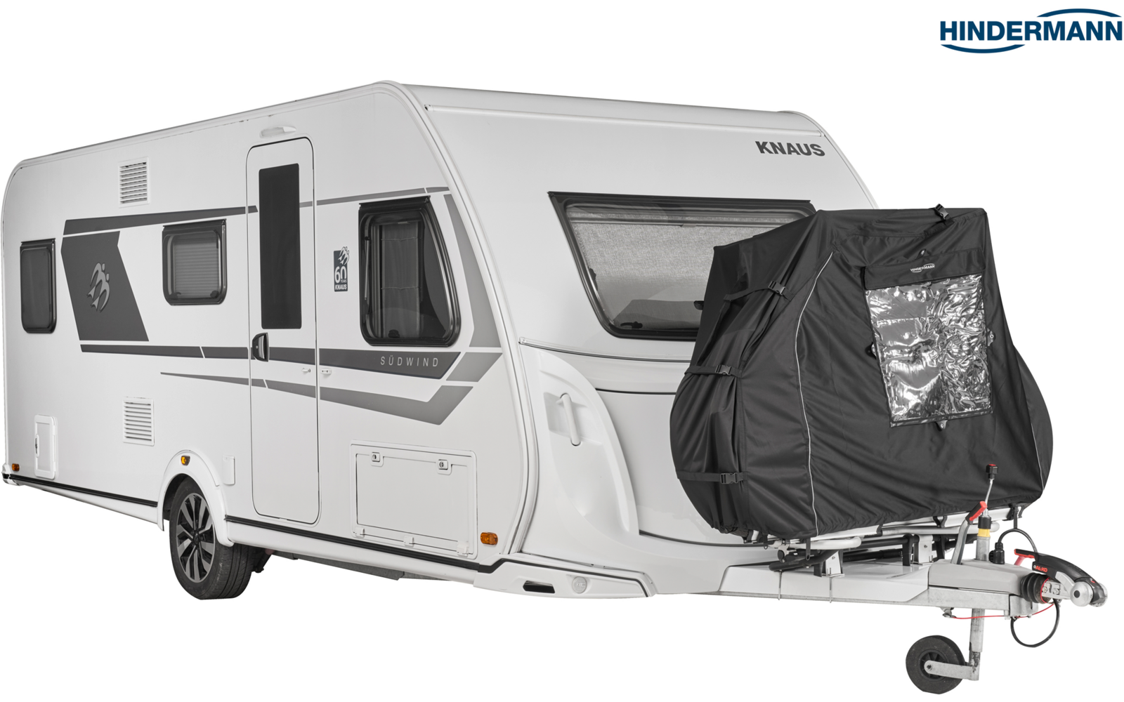 Weißer Wohnwagen mit zwei Seitenfenstern, Eingangstür, Rad, grauem Zierstreifen, schwarzer Abdeckung an der Deichsel, Stützrad sichtbar, Hindermann-Logo oben rechts