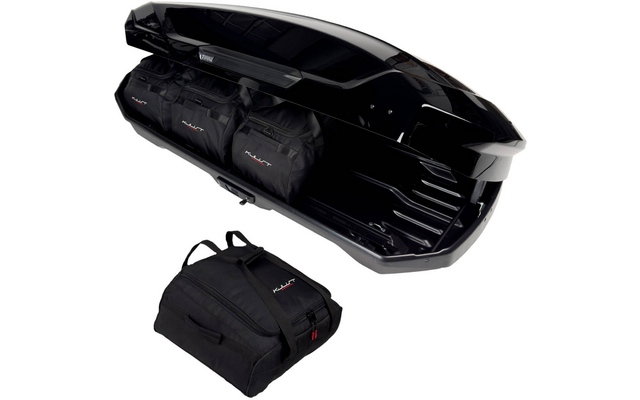 Coffre de toit noir ouvert avec deux sacs de voyage noirs à l'intérieur et un sac de voyage noir à côté