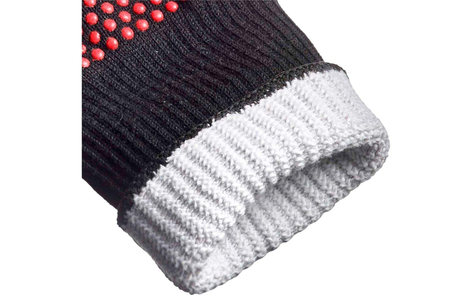 Gros plan d'un gant en tricot noir avec des picots rouges en caoutchouc et un poignet côtelé blanc