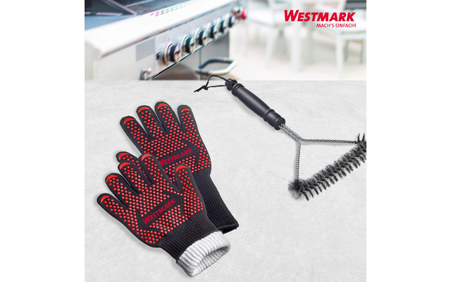 Deux gants noirs avec picots rouges et poignets blancs, inscription "WESTMARK"; à côté une brosse à grill avec trois brosses rondes en fil métallique et poignée noire; en arrière-plan des boutons de cuisinière/grill flous; en haut à droite le logo "WESTMARK"