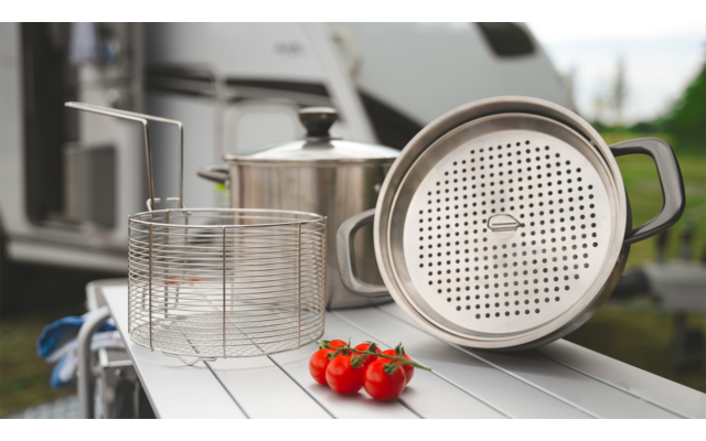 Kaffeemaschine mit Filterbehälter und zwei Tomaten auf einer weißen Oberfläche