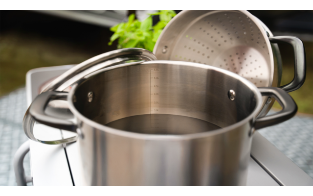 Edelstahltopf mit Sieb und Kochutensilien auf der Arbeitsfläche