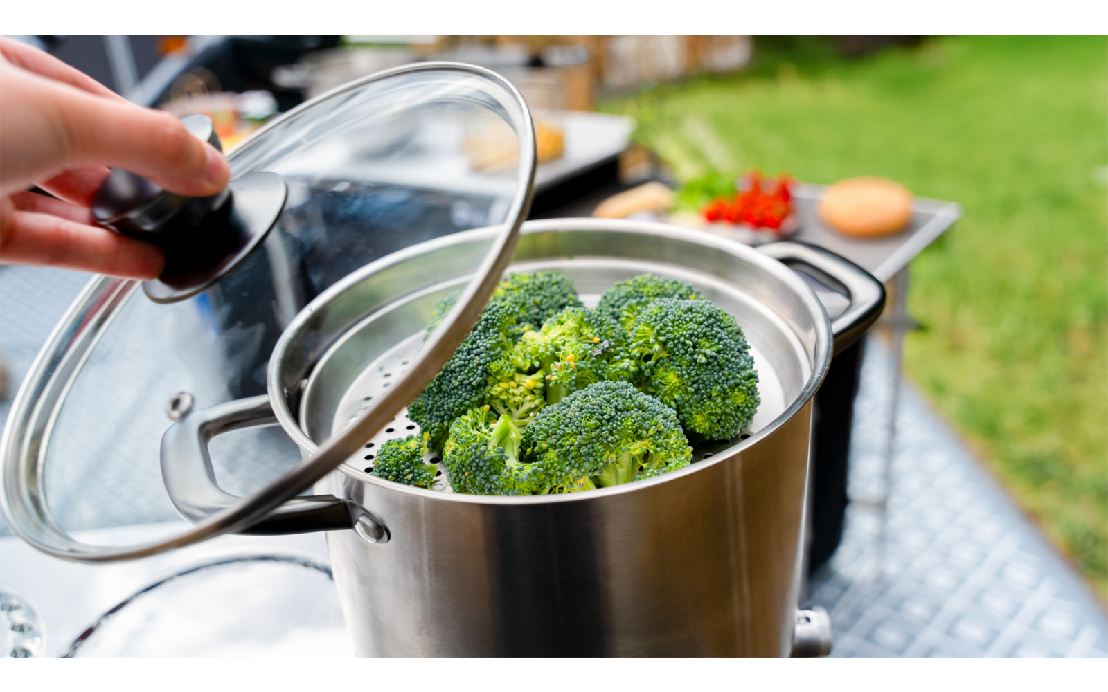 Kochendes Wasser in einem Edelstahltopf mit Brokkoli auf einem Herd im Freien
