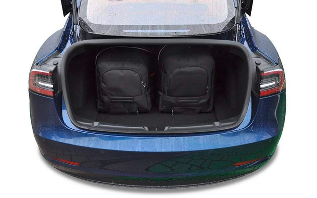 Coffre ouvert d'une voiture bleue avec deux sacs à dos noirs à l'intérieur