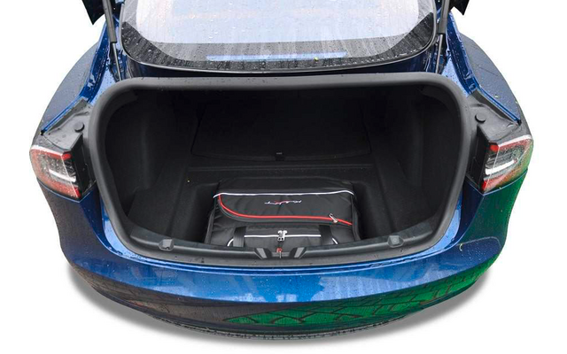 Coffre ouvert d'une voiture bleue avec un sac de voyage noir à l'intérieur