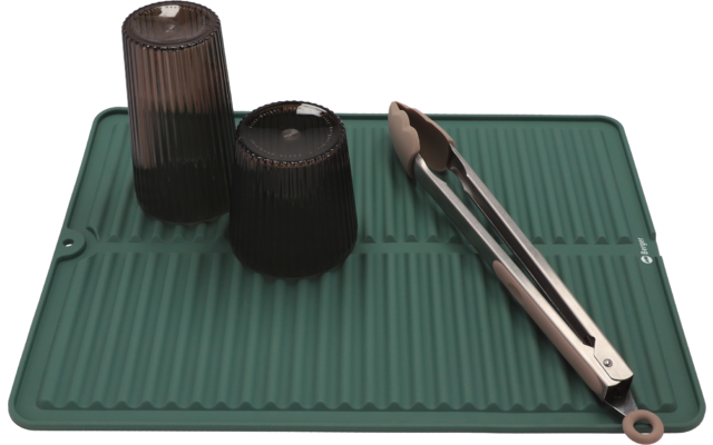 Zwei schwarze Kaffeetassen und ein silberner Milchaufschäumer auf einer grünen Matte