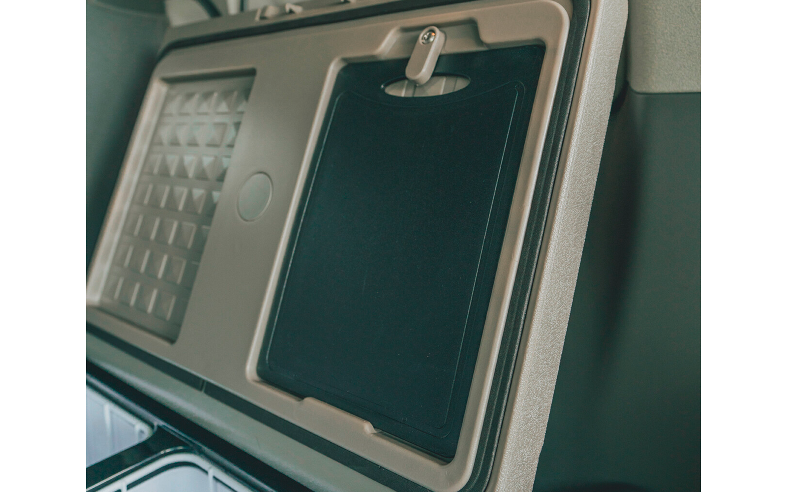 Eingeklappter Tablettentisch an der Rückenlehne eines Sitzes mit Verriegelung und strukturiertem Panel