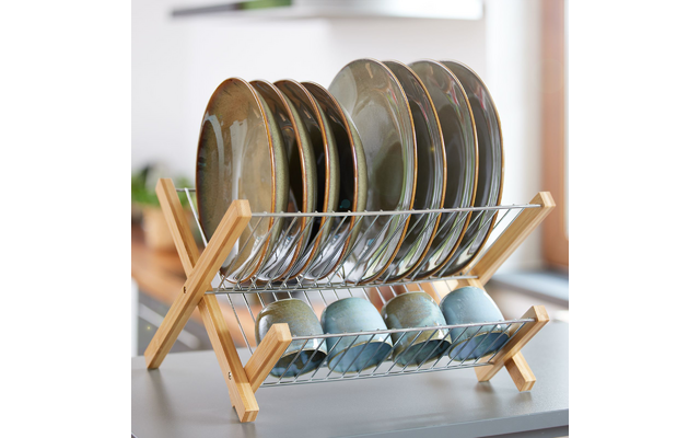 Escurridor metálico con armazón de madera sobre encimera, platos verde-gris colocados verticalmente y varias tazas