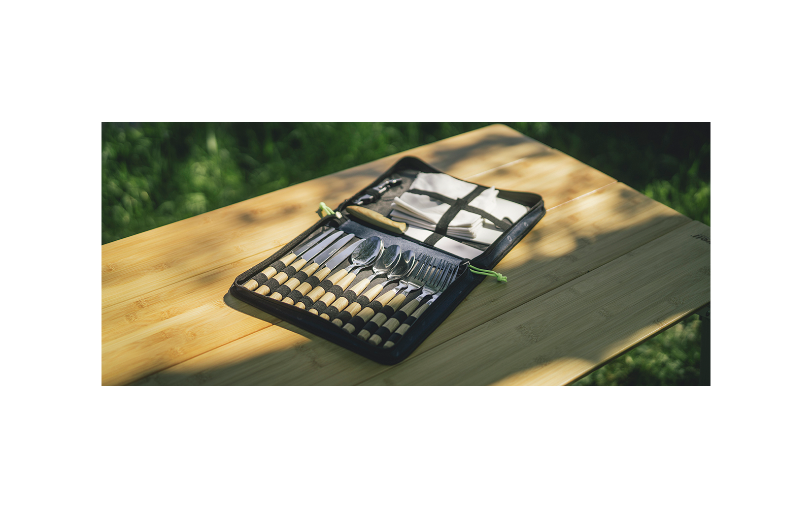 Zwarte metalen kas organizer met meerdere kleine vakken gevuld met verschillende insecten, geplaatst op een lichte houten tafel in zonlicht