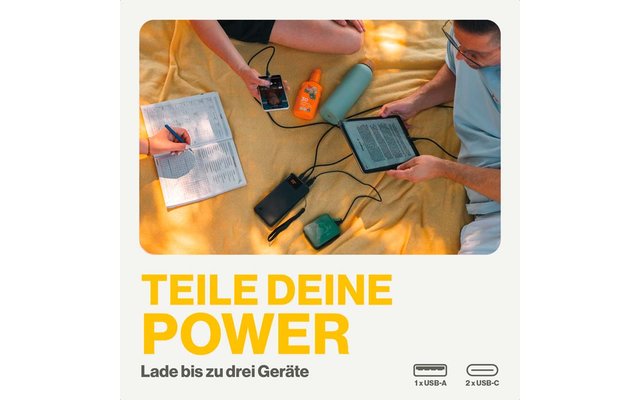 Vier handen bedienen vier verschillende elektronische apparaten op een houten tafel