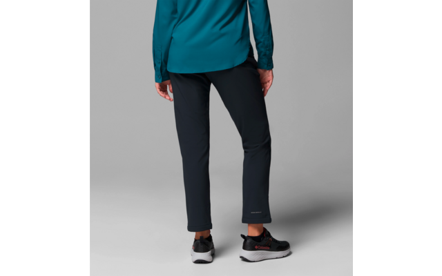 Personne vue de dos, portant un pantalon noir, une veste bleue et des chaussures noires, debout sur un fond gris