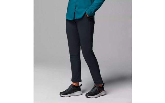 Personne portant un pantalon noir et des chaussures de sport noires avec des semelles blanches, torse partiellement visible avec un haut bleu