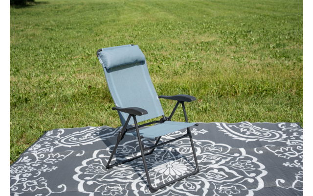 Light blue folding lounge chair with headrest on a gray rug with white pattern on grass