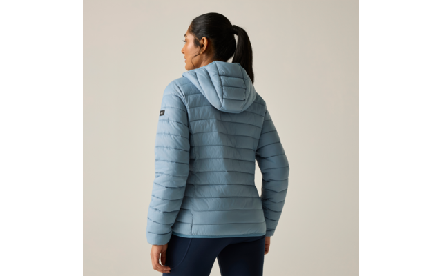 Rückansicht einer Person mit Zopf, die eine hellblaue gesteppte Kapuzenjacke und dunkle Leggings trägt vor hellem Hintergrund
