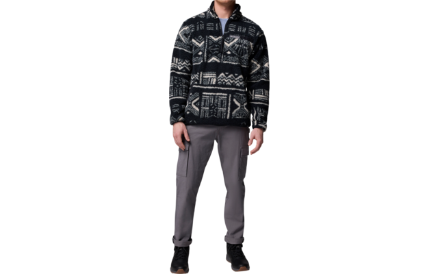 Ein Mann trägt eine schwarze Strickjacke mit weißen Mustern und schwarze Hose