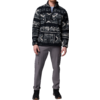 Ein Mann trägt eine schwarze Strickjacke mit weißen Mustern und schwarze Hose