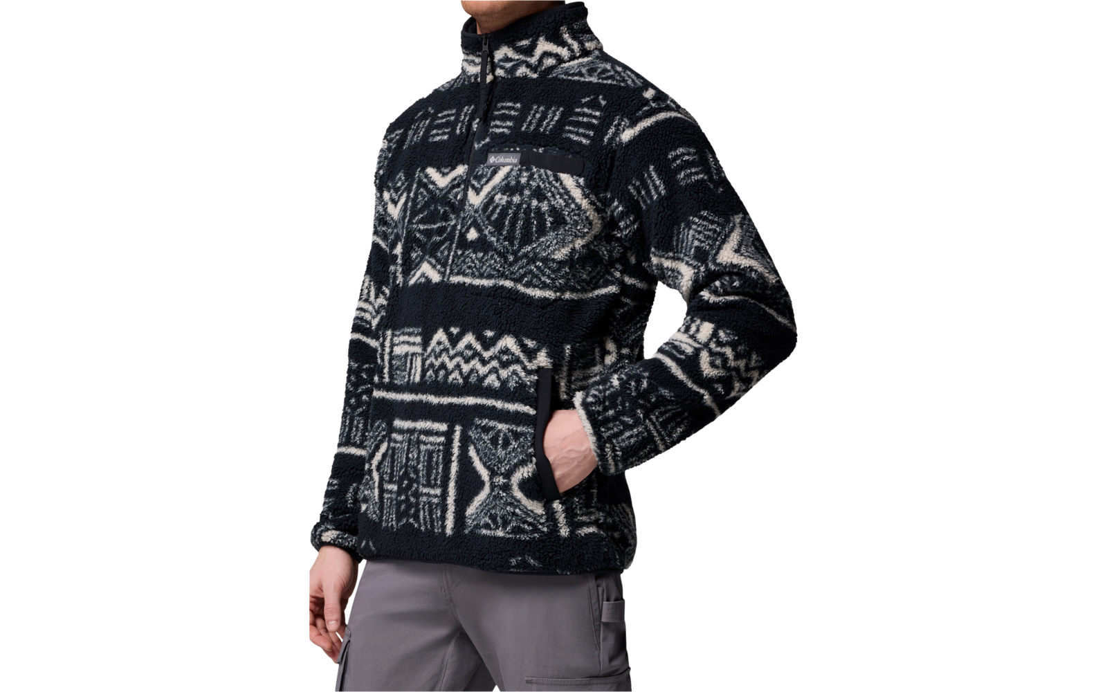 Person trägt eine dunkle Jacke mit weißen nordischen Mustern und hat die Hände in den Taschen