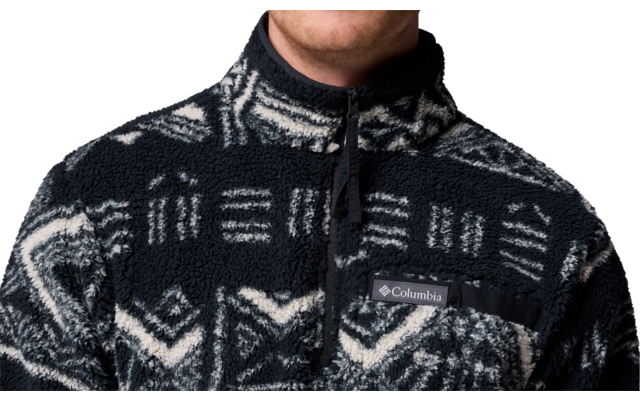 Oberkörper einer Person mit einem dunklen Pullover mit geometrischem Muster