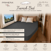 Slaapruimte in camper met rechts French-bedmatras, donkergrijs hoeslaken, twee lichte kussens, raam met zeezicht, houtafwerking; zichtbare tekst 'PRIMERA TRAVEL', 'French Bed'
