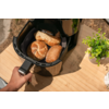 Hand hält den Griff eines offenen Heißluftfritteusen-Korbs mit drei Brötchen auf einer Holzoberfläche, daneben ein kleines grünes Topfpflänzchen