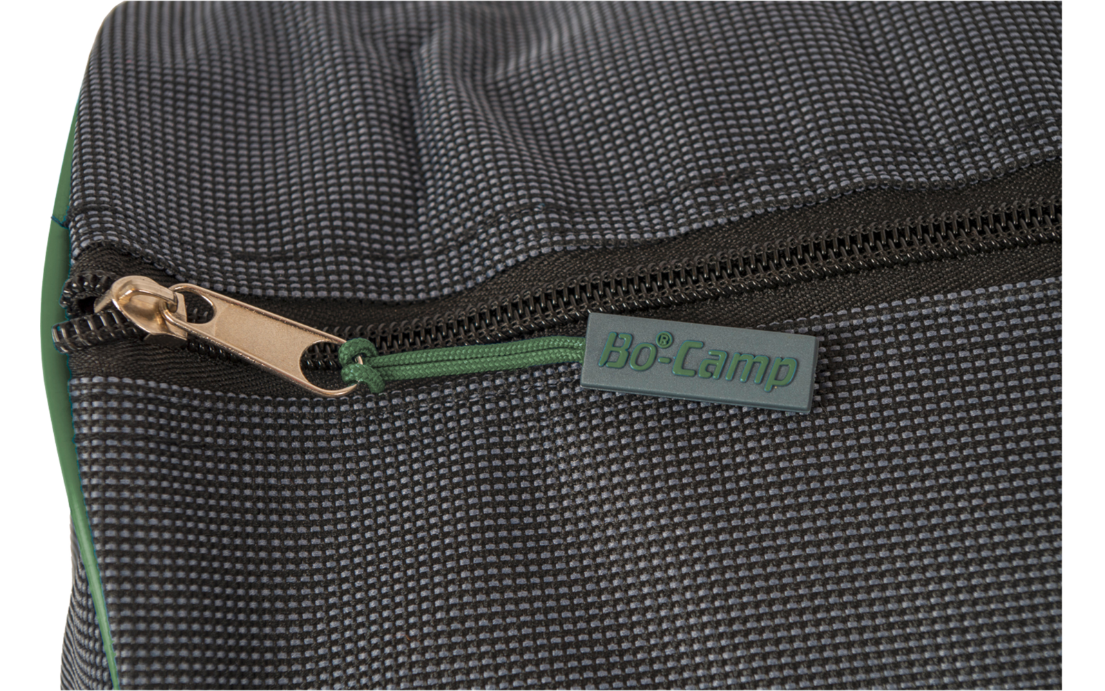 Gros plan sur un tissu texturé gris foncé avec une fermeture éclair, curseur couleur bronze et étiquette verte "Bo-Camp"