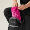 Hände schieben eine gefaltete pinke Packjacke mit dem Schriftzug 'KID'S PACK-IT JACKET' in einen schwarzen Rucksack mit Aufschrift 'REGATTA GREAT OUTDOORS'