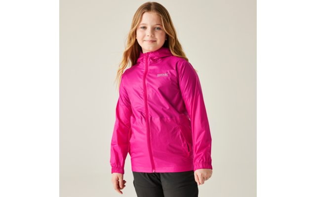 Girl with long blond hair wearing a pink jacket, standing against a light background and smiling