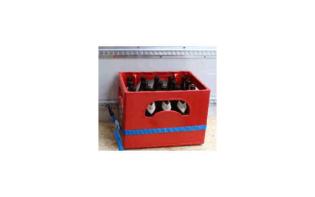 Red plastic crate with 16 empty beer bottles on a wooden floor