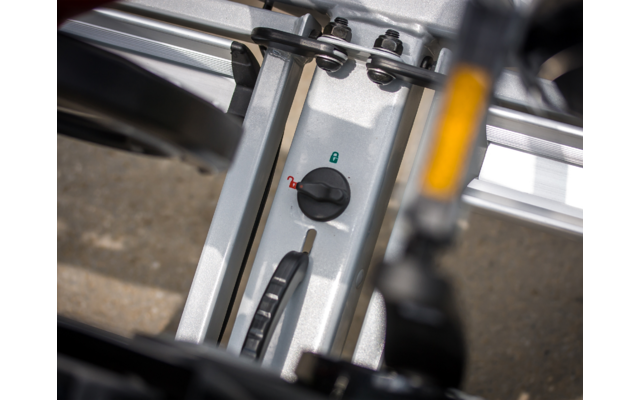 Nahaufnahme eines silbernen Metallrahmens mit einem schwarzen Drehknopf mit grüner und roter Markierung, einer Schiene und einem schwarzen Hebel