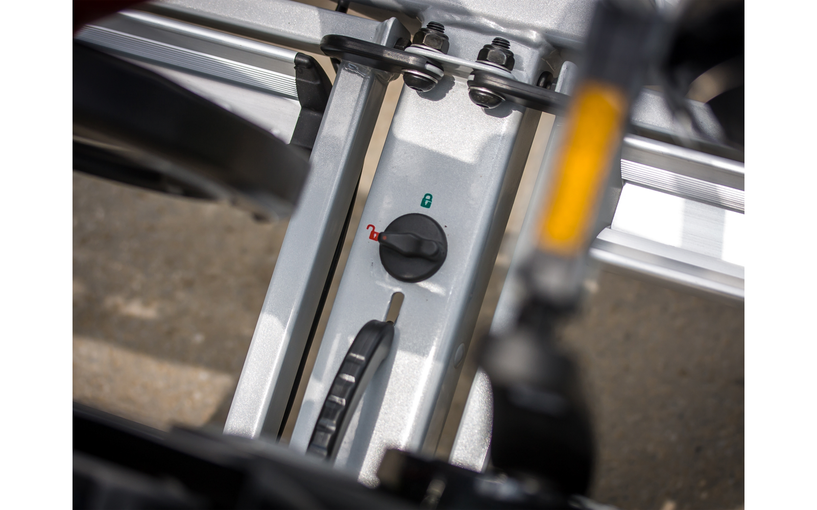 Nahaufnahme eines silbernen Metallrahmens mit einem schwarzen Drehknopf mit grüner und roter Markierung, einer Schiene und einem schwarzen Hebel