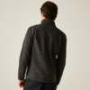 Rückenansicht einer Person mit kurzen dunklen Haaren, die einen dunkelgrauen Pullover mit Stehkragen und schwarze Hosen vor hellem Hintergrund trägt