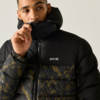 Person zieht den Reißverschluss einer schwarzen Steppjacke mit hohem Kragen hoch, unterer Teil mit camouflageähnlichem Muster