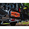 Close-up of a red illuminated bicycle rear light attached to a metal bike rack, multiple bicycles in the background