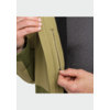 Deux mains tiennent la fermeture éclair d'une poche intérieure d'une veste vert olive; un T-shirt gris foncé est visible en dessous