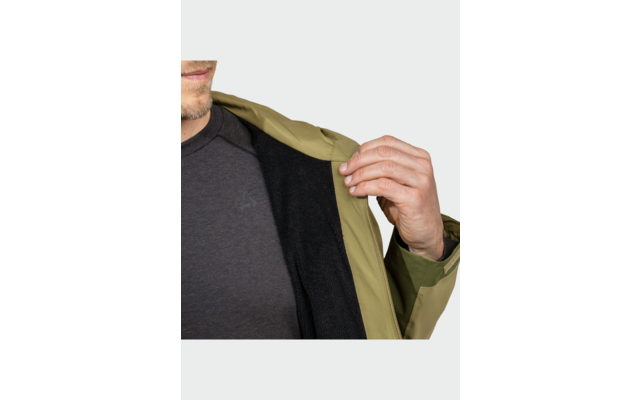 Vue partielle du bas du visage d'une personne avec barbe de quelques jours; main tenant une veste vert olive ouverte montrant une doublure noire; t-shirt gris foncé visible; bracelet noir au poignet
