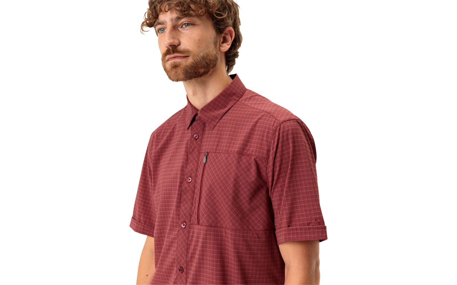 Persoon met krullend bruin haar en baard, draagt rood geruit kort mouwig overhemd, kijkt naar links