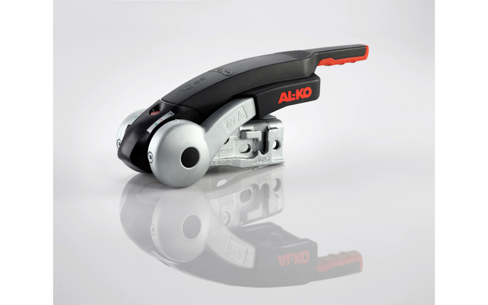 Metalen apparaat met ronde zilveren wiel, zwart kunststof handvat met rode rand en rode tekst "AL-KO" op een lichte achtergrond, reflectie eronder